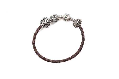 A Pandora brown leather bracelet and three retired charms in sterling silver