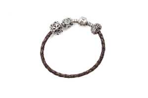 A Pandora brown leather bracelet and three retired charms in sterling silver