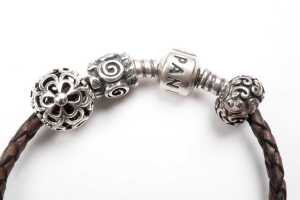 A Pandora brown leather bracelet and three retired charms in sterling silver - 2