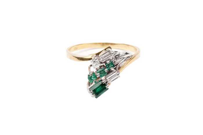 An emerald and diamond ring in 18 carat yellow gold