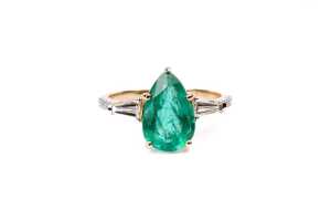 An emerald and diamond ring in 14 carat yellow gold