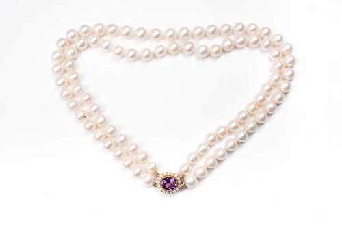 A double strand of pearls to an amethyst and pearl clasp in 9 carat yellow gold