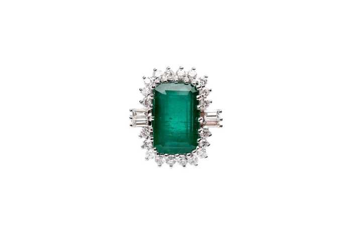 An emerald and diamond ring in 18 carat white gold