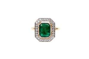 An emerald and diamond ring set in 18 carat yellow gold