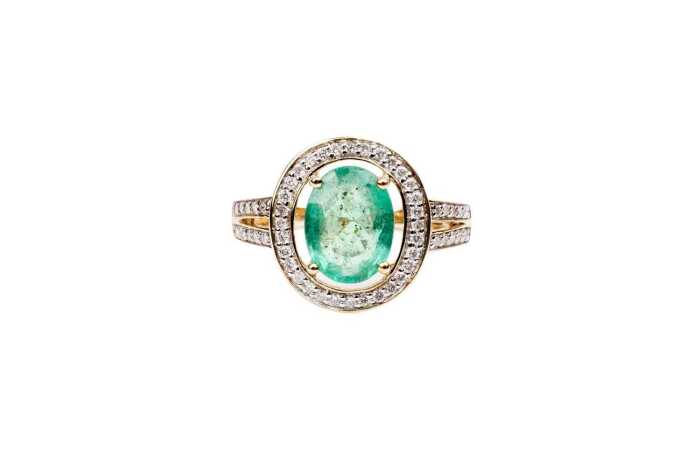 An emerald and diamond ring in 14 carat yellow gold