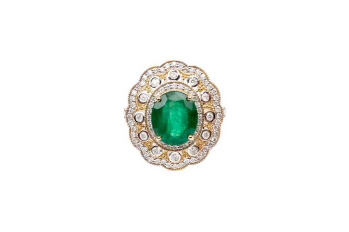 An emerald and diamond ring in 14 carat yellow gold