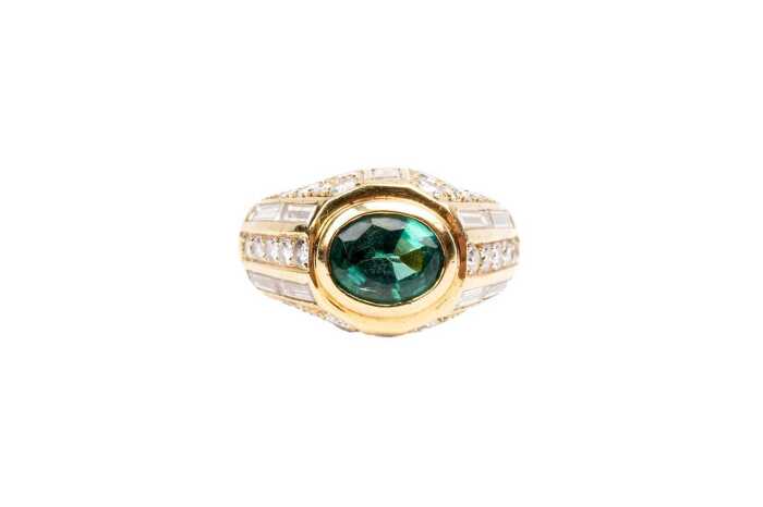 An emerald and diamond ring in 18 carat yellow gold