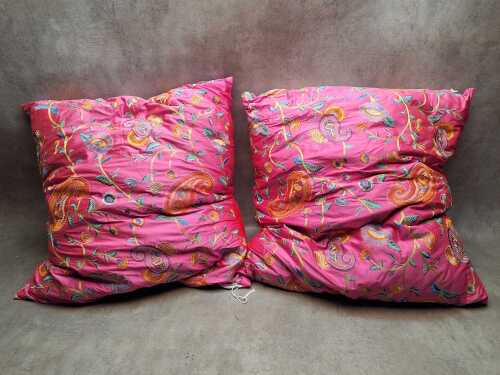 Two bright pink embroidered cushions with feather filled inserts