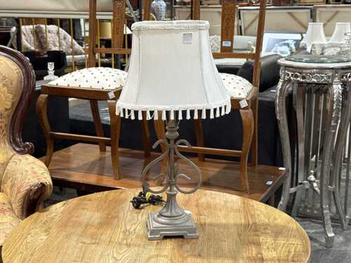 Ornate table lamp with grey composite body and white fringed shade