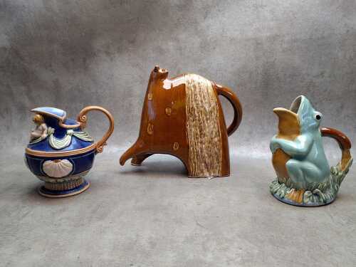 Three whimsical ceramic jugs including a frog and a cat-shaped jug.