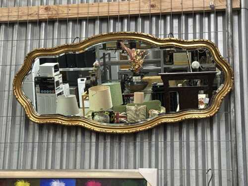 Ornate gilt wall mirror featuring a wavy design frame