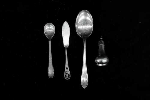 Three sterling silver spoons and a pepper pot, weight 97g, including Georg Jensen