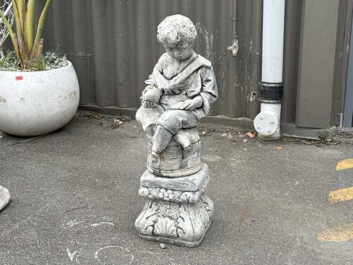 Resin garden statue of seated boy on plinth
