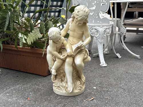Resin garden statue of two figures reading a book