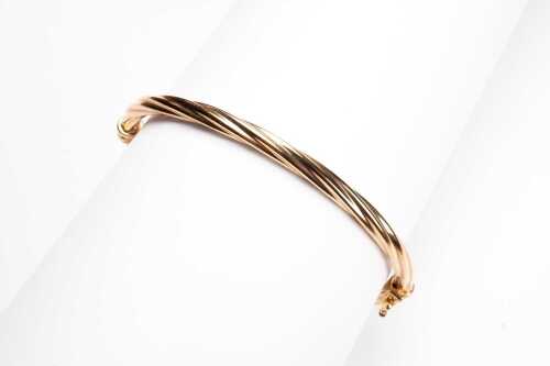 A twist hinged bangle in 9 carat yellow gold.