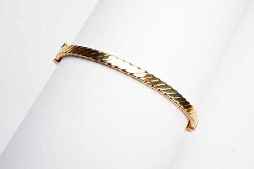 A carved hinged bangle in 9 carat yellow gold.