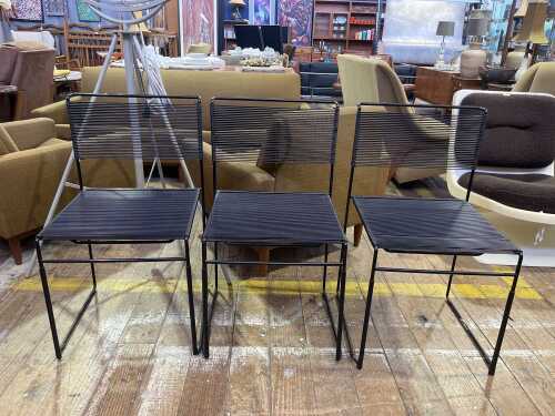 Three black spaghetti chairs