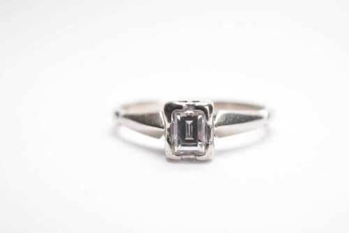 An emerald cut bezel set diamond ring in platinum.