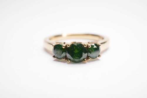 A green sapphire trilogy ring in 9ct yellow gold.