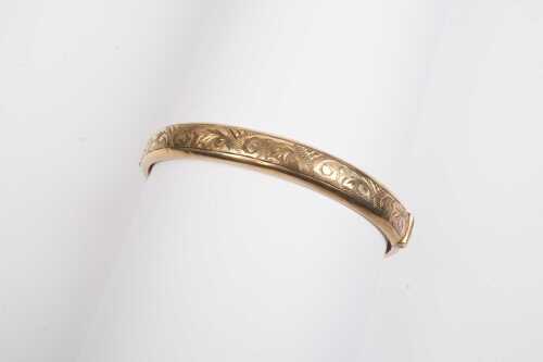 A vintage hinged engraved bangle in 9ct yellow gold.