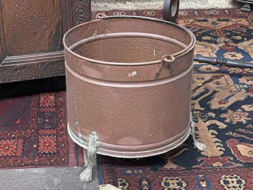 A vintage copper bucket with wrought iron handle and cast brass claw feet