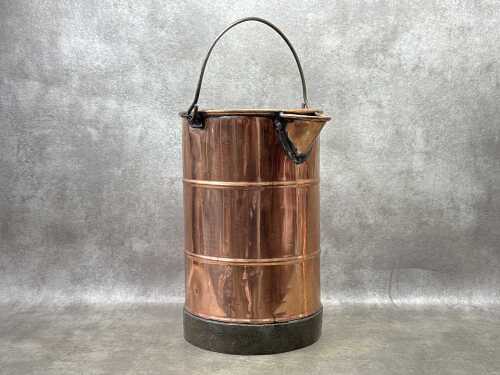 An antique copper water bucket with iron handle and base
