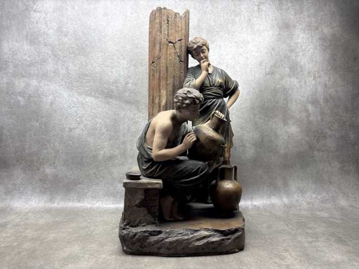 An antique ceramic sculpture depicting a Classical scene of decorators