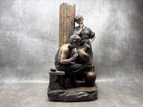 An antique ceramic sculpture depicting a Classical scene of decorators