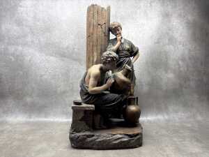 An antique ceramic sculpture depicting a Classical scene of decorators