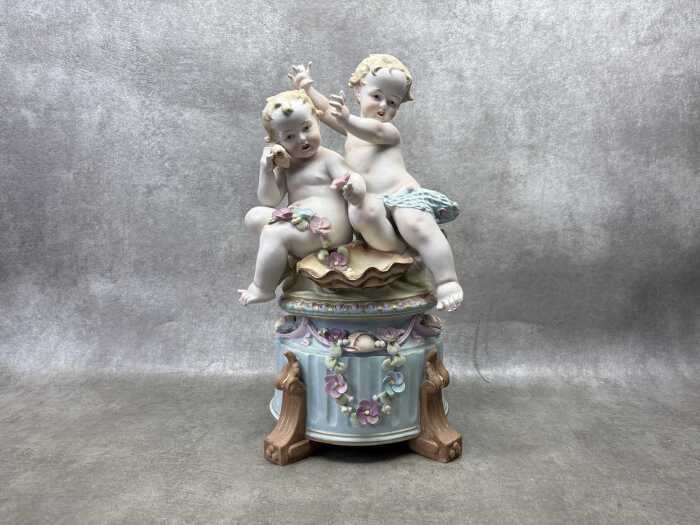 A German hand painted bisque porcelain figure of two babies playing in the garden