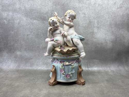 A German hand painted bisque porcelain figure of two babies playing in the garden