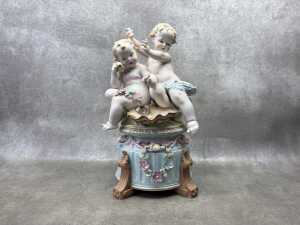 A German hand painted bisque porcelain figure of two babies playing in the garden