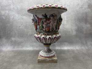 A Capodimonte Italian porcelain urn with hand painted relief scenes of puttis dancing and camping