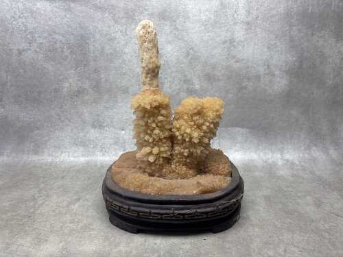 A yellow Calcite Stalactite specimen on timber stand